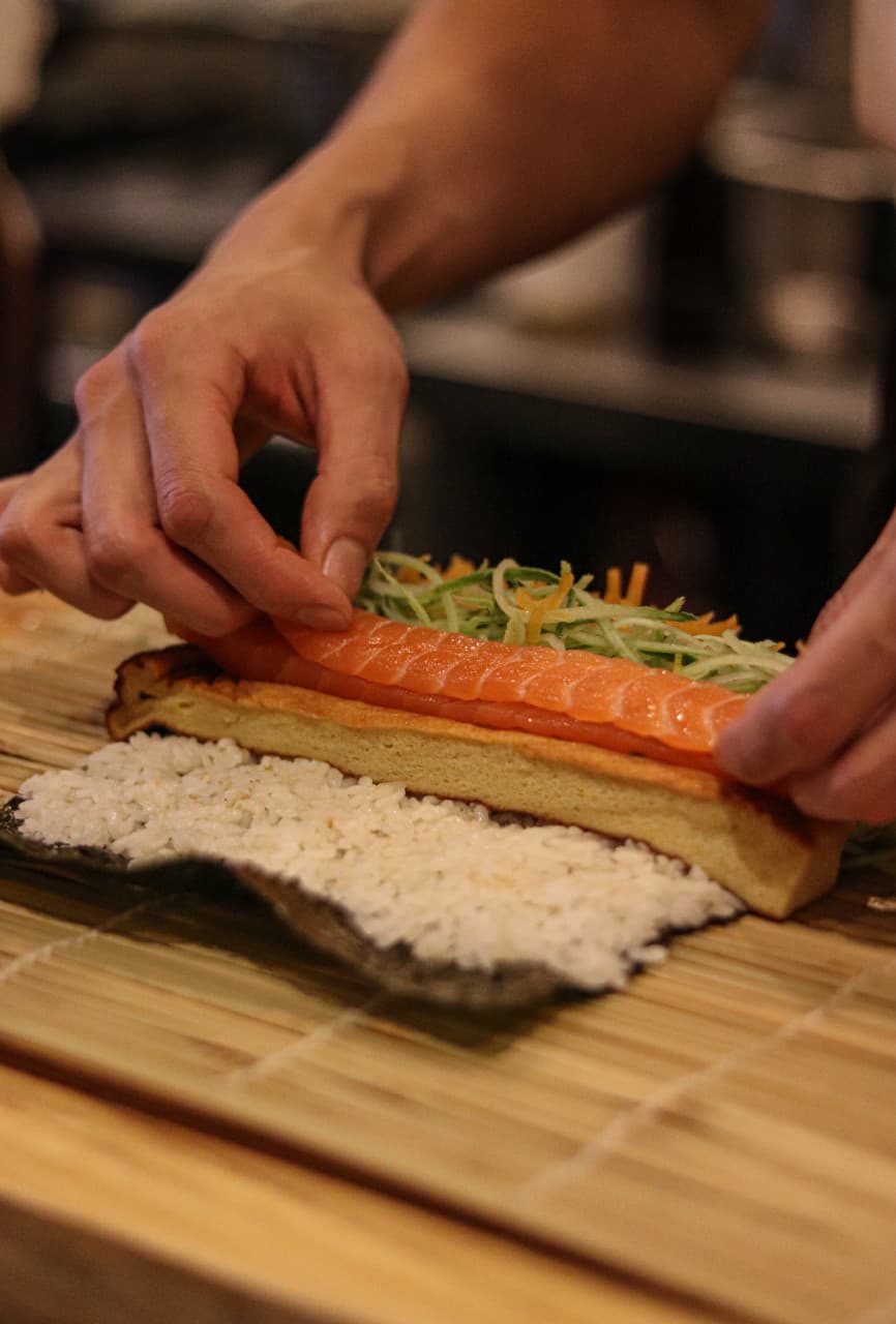 대구광역시 중구 마리타운 대구 이자카야 다찌석에서 주방장이 연어와 채소를 넣은 1인 후토마키를 만드는 과정. 은은한 조명 아래 식재료 질감이 돋보이는 혼술 안주.