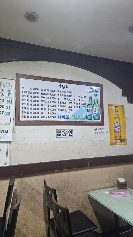 부산광역시 동구 솔잎국수 초량 포장마차 내부. 벽면에 부착된 차림표와 낙서들 아래 1인 혼술이 가능한 테이블과 의자가 배치된 실내 전경을 보여줌.