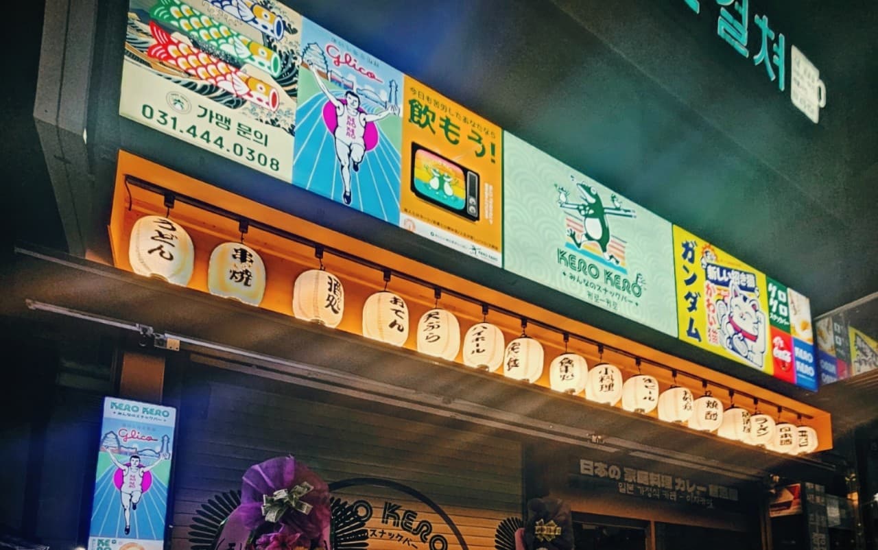 경기도 안양시 이자카야 케로케로 안양점 경기 입구의 일본식 간판과 흰색 초롱 조명. 1인 혼술용 다찌석이 구비된 매장 외관에 나열된 등불과 캐릭터 표지판.