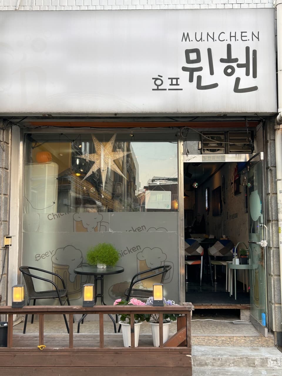 경기도 안양시 뮌헨호프 경기 안양 맥주 호프 - 별 모양 조명이 켜진 유리창 앞 야외 1인 좌석과 원형 테이블이 놓인 혼술 공간