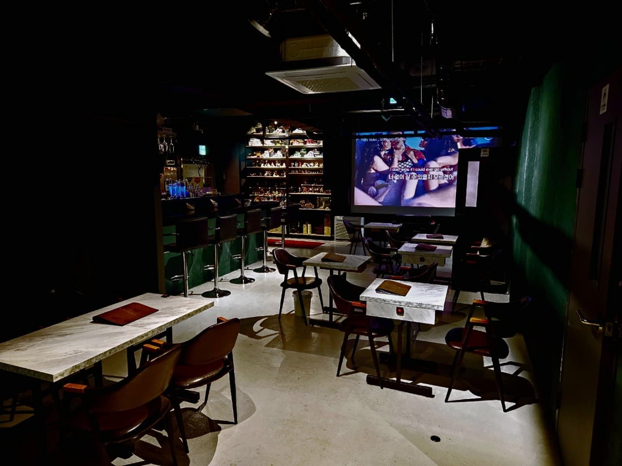 경기도 성남시 JANA BAR & PUB 바 - 어두운 조명 아래 1인 다찌석과 마블 테이블, 대형 스크린이 배치된 혼술 공간