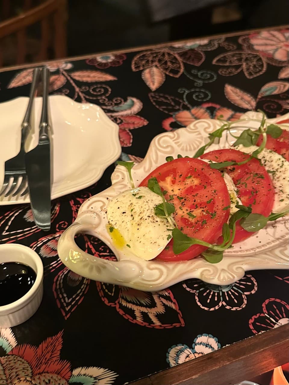 경기도 성남시 성지술례 바(Bar) 다찌석에서 즐기는 혼술 토마토 카프레제. 꽃무늬 식탁보 위 하얀 접시에 담긴 치즈와 토마토 질감, 발사믹 소스가 놓인 1인 테이블 구성.