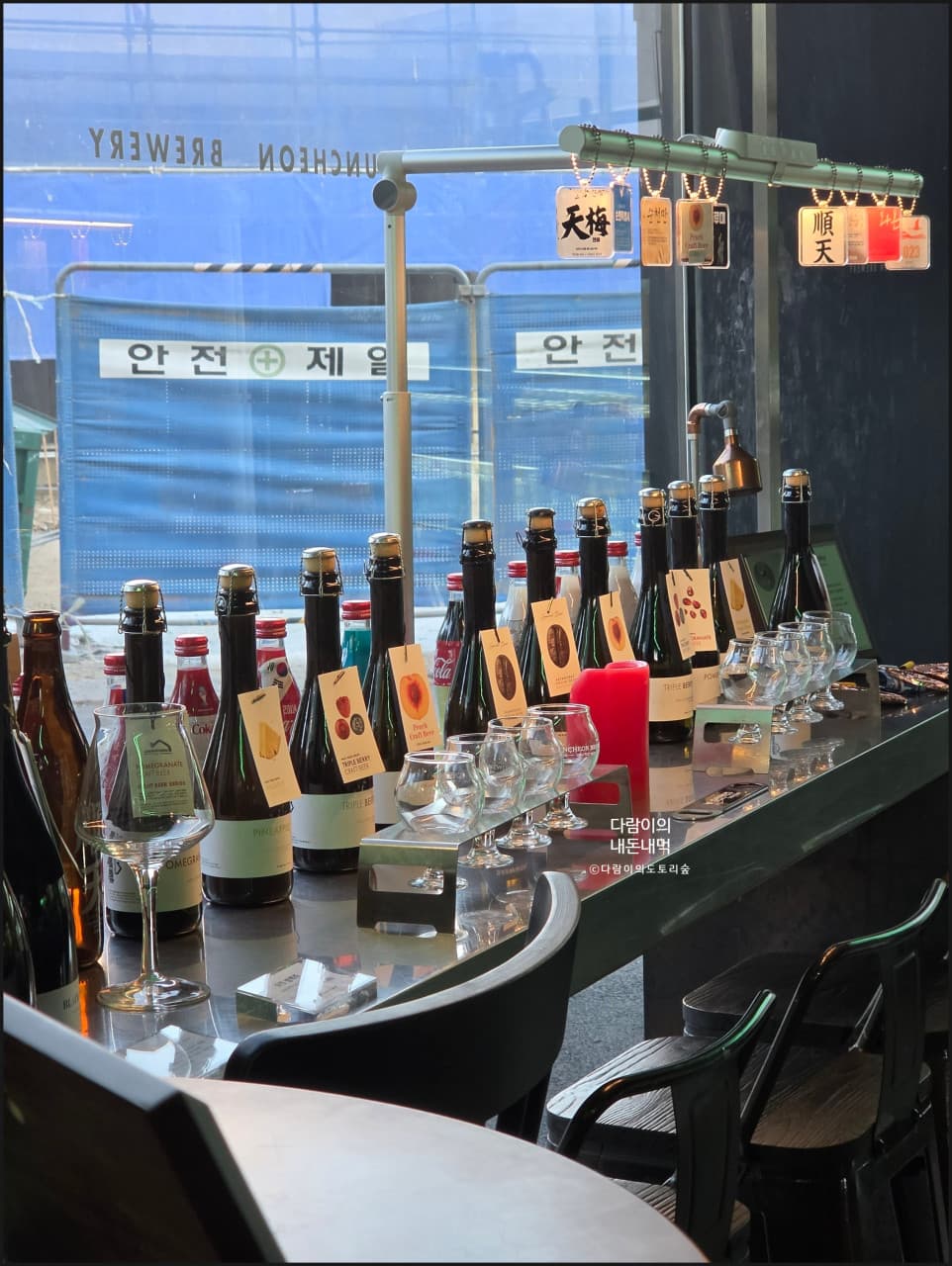 전남광주통합특별시 순천시 순천양조장 맥주 호프 - 조명 아래 1인 다찌석에 일렬로 늘어선 수제 맥주 병들과 전용 잔이 배치된 혼술 자리