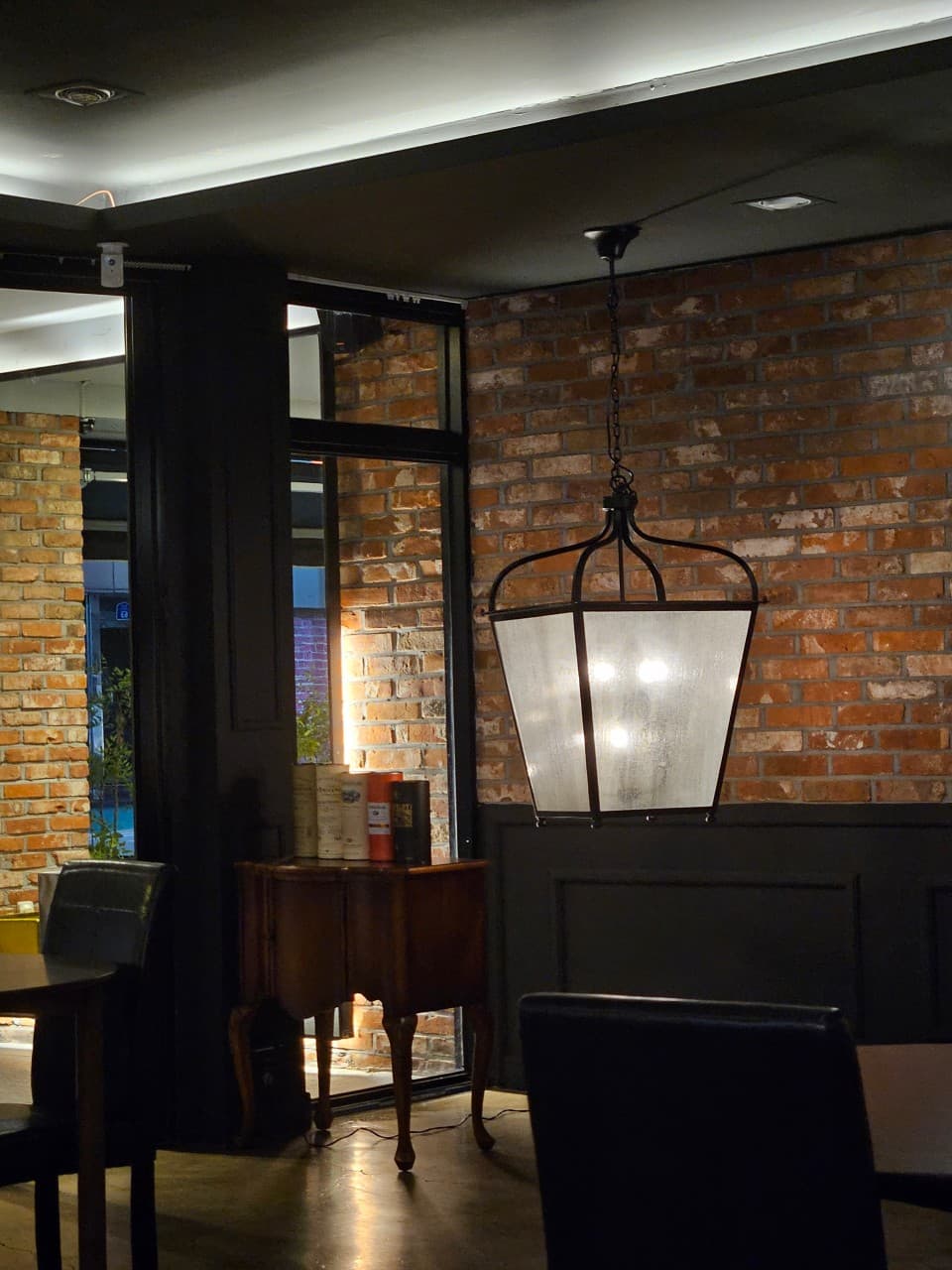 전남광주통합특별시 목포시 밀물 전남 바(Bar)의 붉은 벽돌 벽과 펜던트 조명 아래 배치된 혼술용 1인 좌석. 목재 가구와 위스키 병이 진열된 다찌석 부근의 실내 전경.
