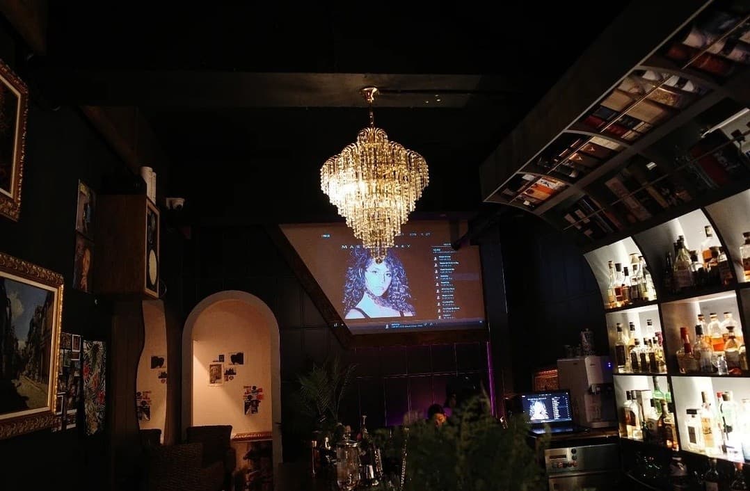 전남광주통합특별시 여수시 몰트바여수 전남 바(Bar) - 대형 샹들리에와 위스키 선반이 배치된 다찌석에서 1인 혼술을 즐기는 상황
