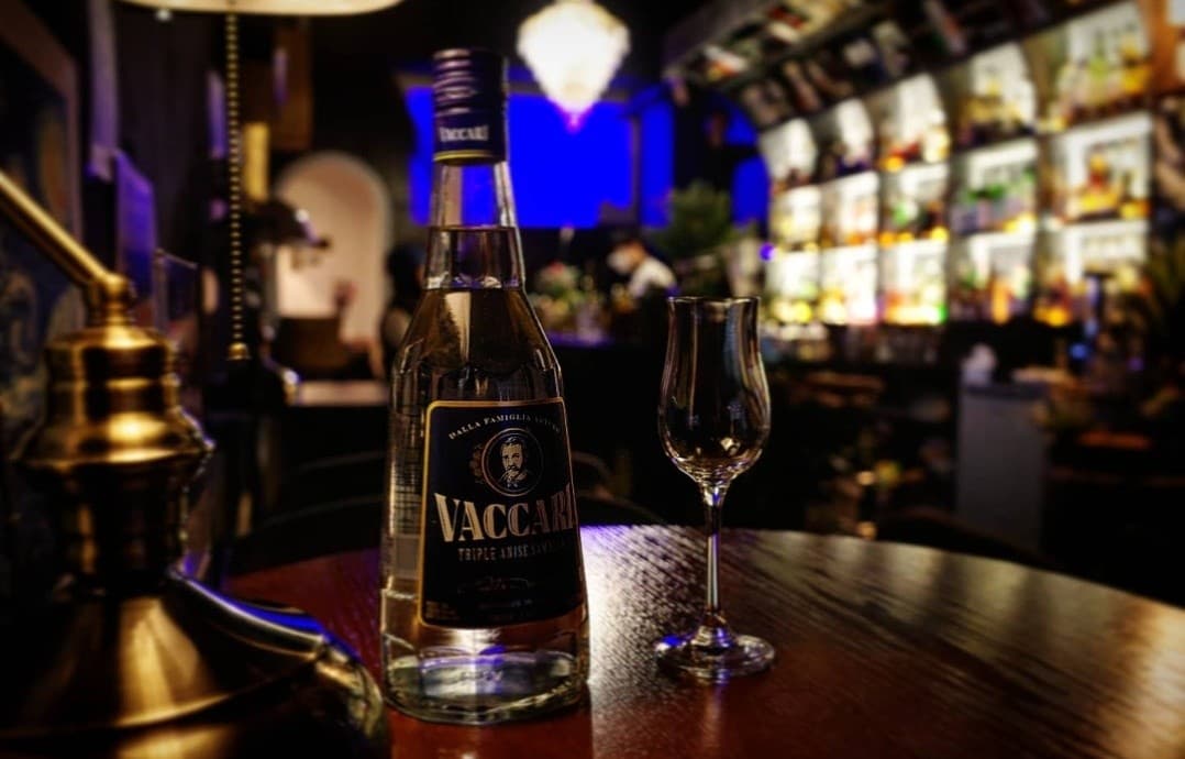 전남광주통합특별시 여수시 몰트바여수 전남 바(Bar)의 다찌석 앞 조명 아래 놓인 바카리 병과 잔. 술병이 가득한 진열장을 배경으로 차분하게 즐기는 1인 혼술 상황.