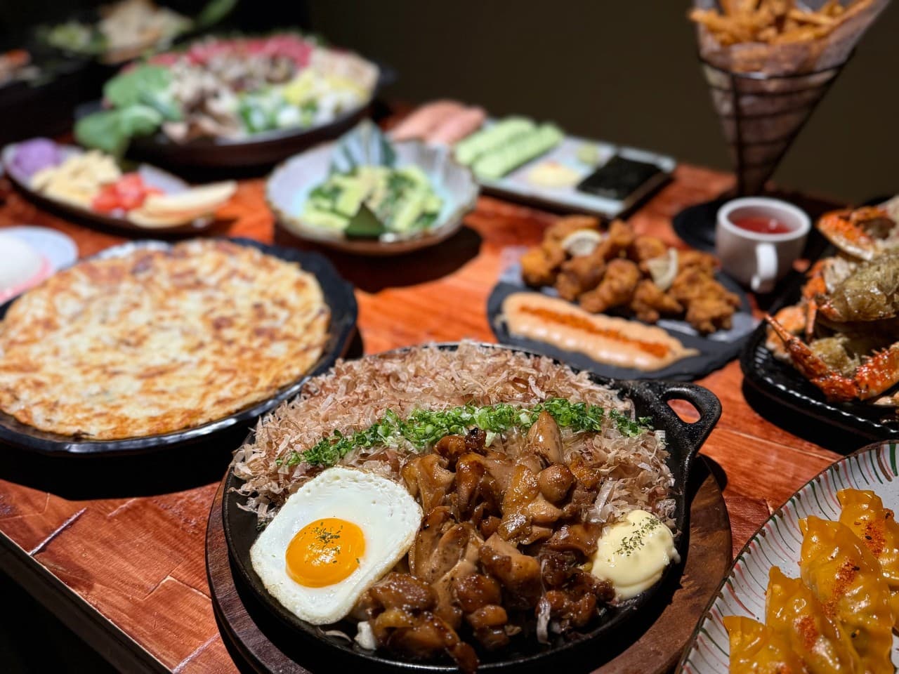 인천광역시 부평구 코코스키 부평점 인천 이자카야 다찌석 조명 아래 가다랑어포가 얹어진 철판 요리와 바삭한 튀김 등 1인 혼술 차림이 놓인 상황