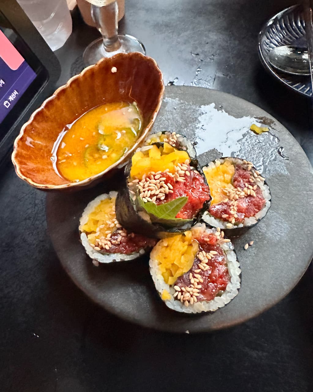인천광역시 연수구 요리주점 심도 송도트리플점 인천 다찌석에 차려진 1인 혼술 메뉴. 참깨가 뿌려진 육회 마끼와 소스, 태블릿이 놓인 어두운 테이블 위 조명.