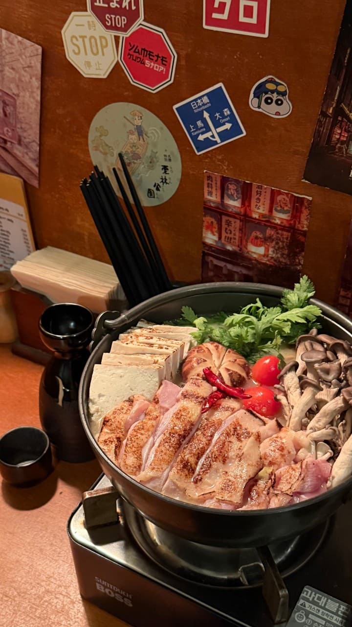 인천광역시 미추홀구 이자카야 야키토리 니센 인천 - 1인 다찌석 조명 아래 구운 닭고기와 버섯이 담긴 나베. 사케 도쿠리와 함께 차려진 혼술 상차림.