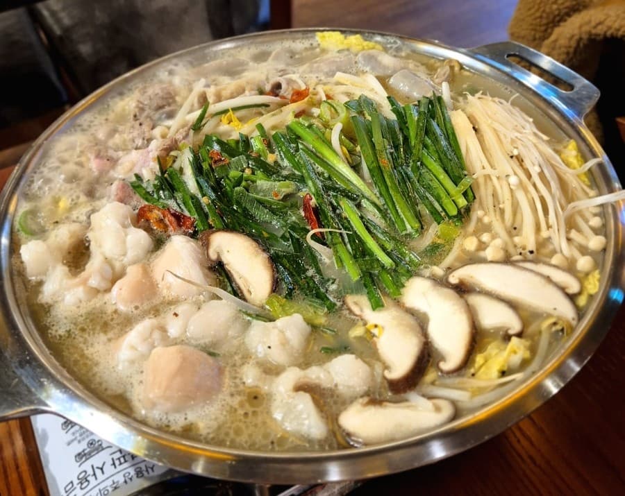 세종특별자치시 나성북1로 타키 세종나성점 다찌석 1인 혼술. 보글보글 끓는 대창 전골의 부추와 버섯, 뽀얀 국물 질감이 조명 아래 드러난 기타 안주 요리 식사 상황.