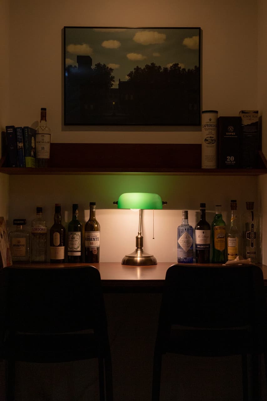 서울특별시 마포구 책바 서울 바(Bar) 초록색 스탠드 조명 아래 1인 다찌석과 진열된 위스키병들. 혼술을 위한 의자와 책장이 마련된 실내 상황을 보여줌.