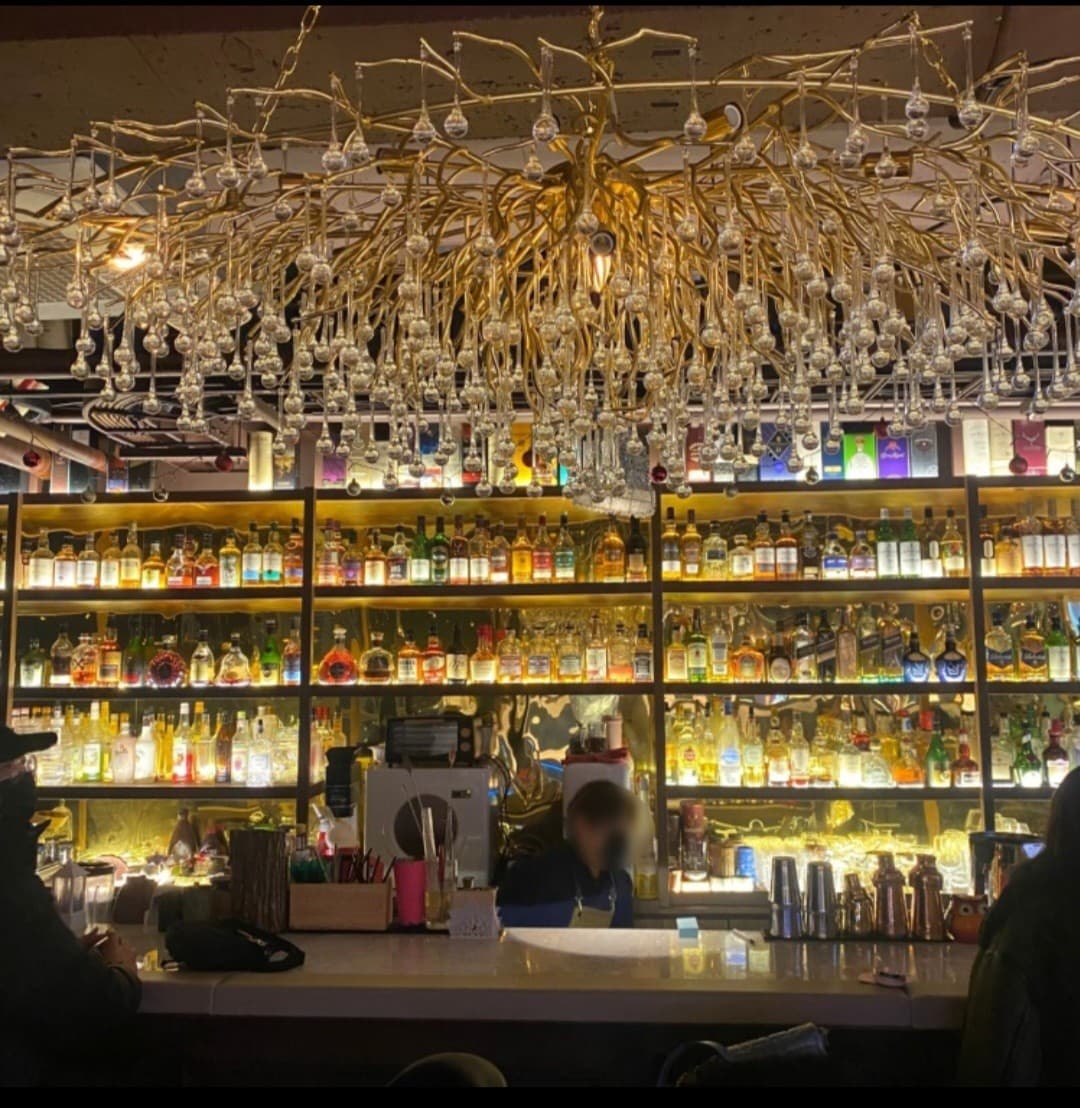 서울특별시 강서구 깔루아 서울 바(Bar) 다찌석에서 금빛 샹들리에와 진열된 술병들을 마주하며 혼술을 즐기는 1인석 카운터 상황