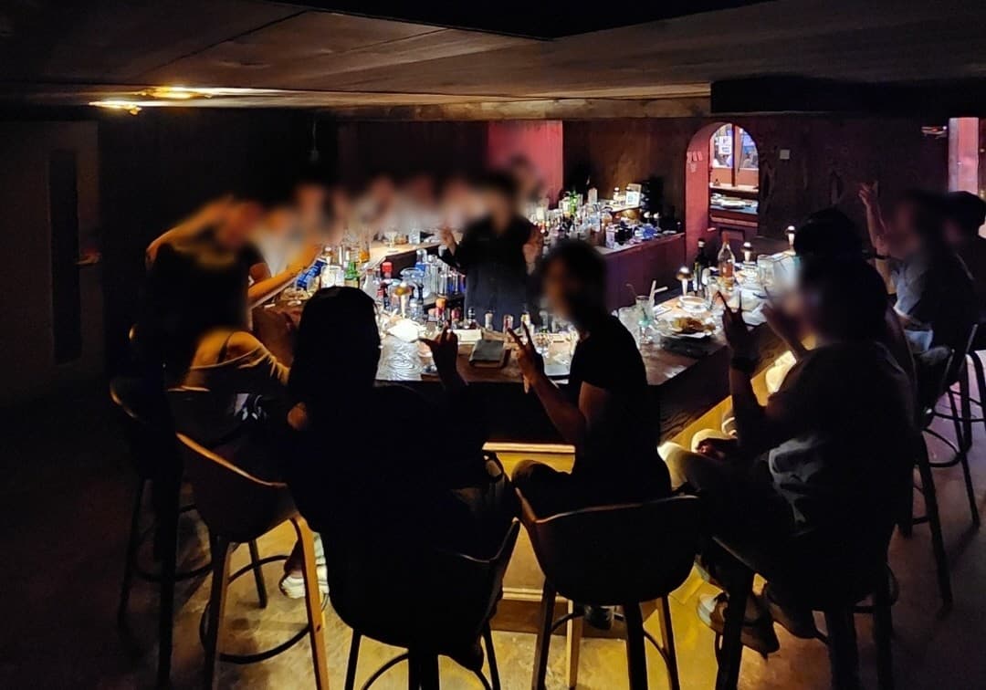 대전광역시 유성구 블렌딩바 대전혼술바 봉명점 바(Bar) - 노란빛 간접 조명이 비치는 다찌석 카운터에서 1인 혼술을 즐기는 상황