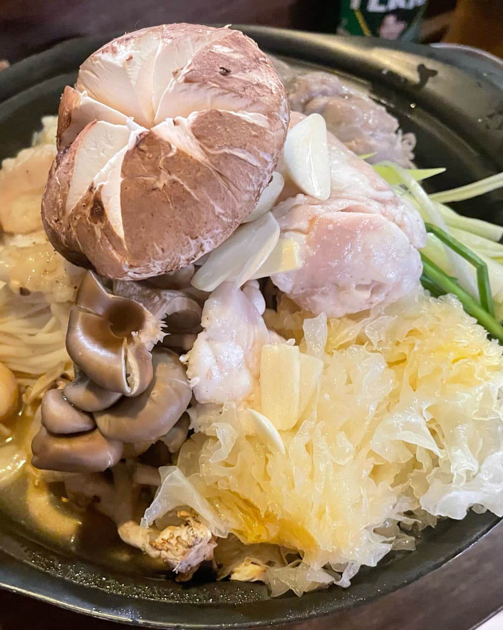 대전광역시 서구 불오름 대전 이자카야 다찌석에서 즐기는 1인 전골. 표고버섯과 백목이버섯의 질감이 강조된 안주가 조명 아래 놓인 혼술 상황을 묘사함.