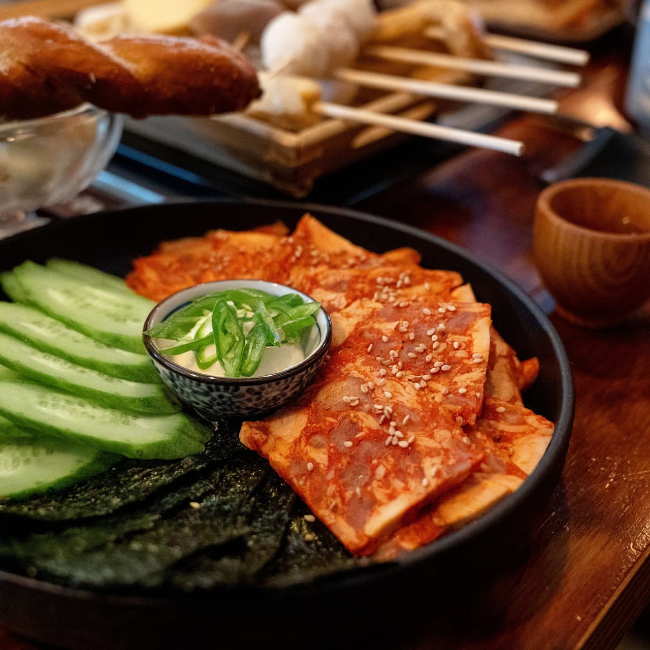 대전광역시 서구 요리주점 철길부산집 대전괴정점 다찌석 혼술. 은은한 조명 아래 놓인 붉은 명란구이와 얇게 썬 오이, 김의 질감과 뒤로 보이는 어묵 꼬치.