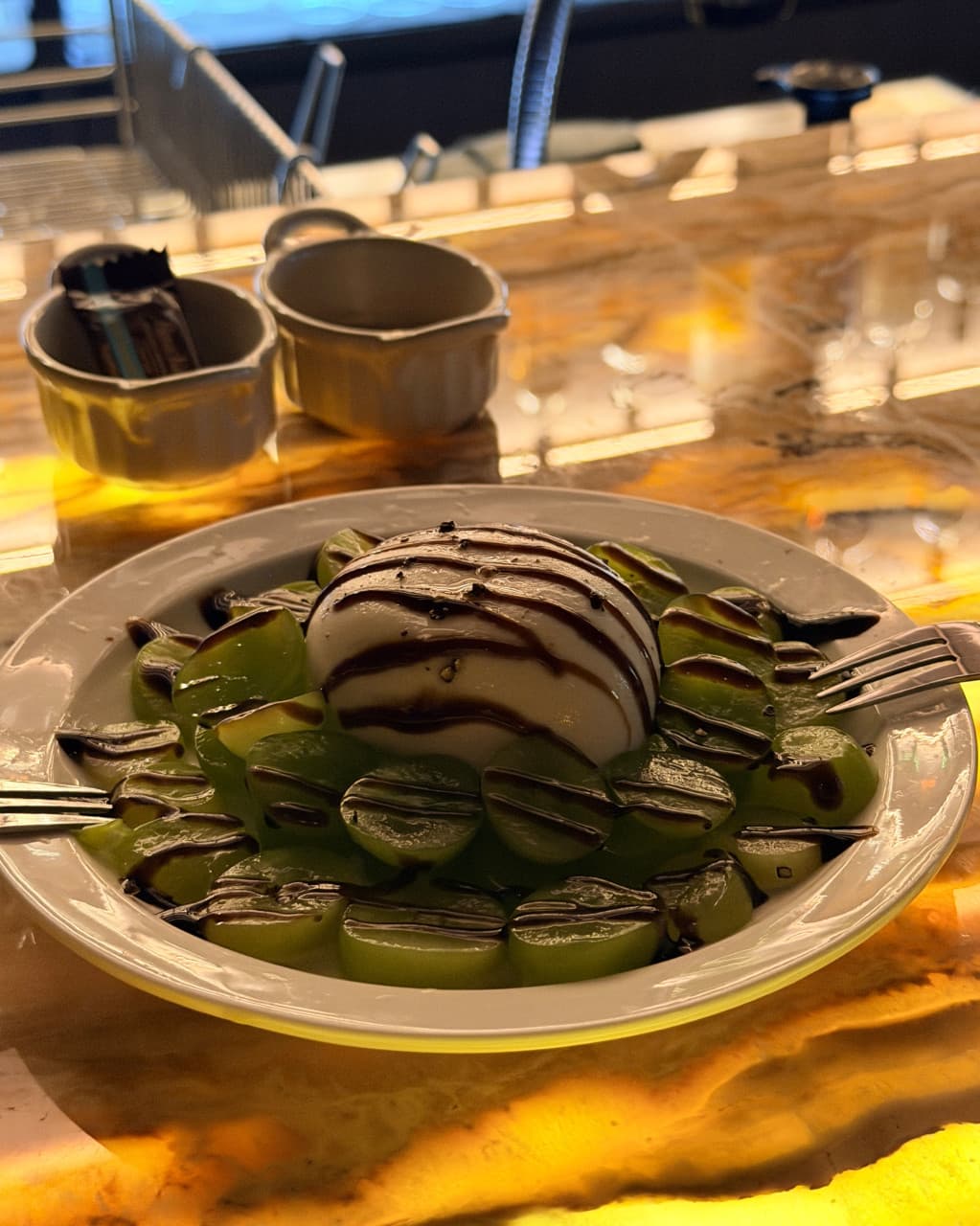 대전광역시 유성구 루미테라 대전 바(Bar). 황색 조명이 빛나는 1인 다찌석에 차려진 부라타 치즈와 청포도. 발사믹 소스의 질감이 강조된 안주와 함께 즐기는 혼술 상황.