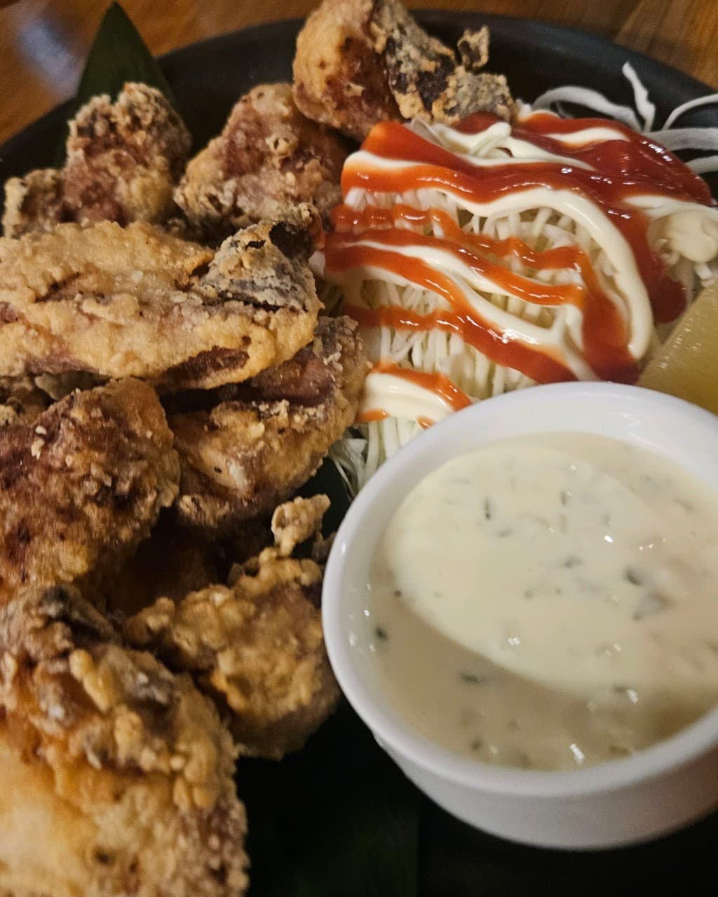 대전광역시 서구 탄방 도깨비 대전 이자카야 다찌석 조명 아래 놓인 바삭한 식감의 치킨 가라아게와 샐러드. 혼술 상황에 적합한 1인 메뉴 구성.