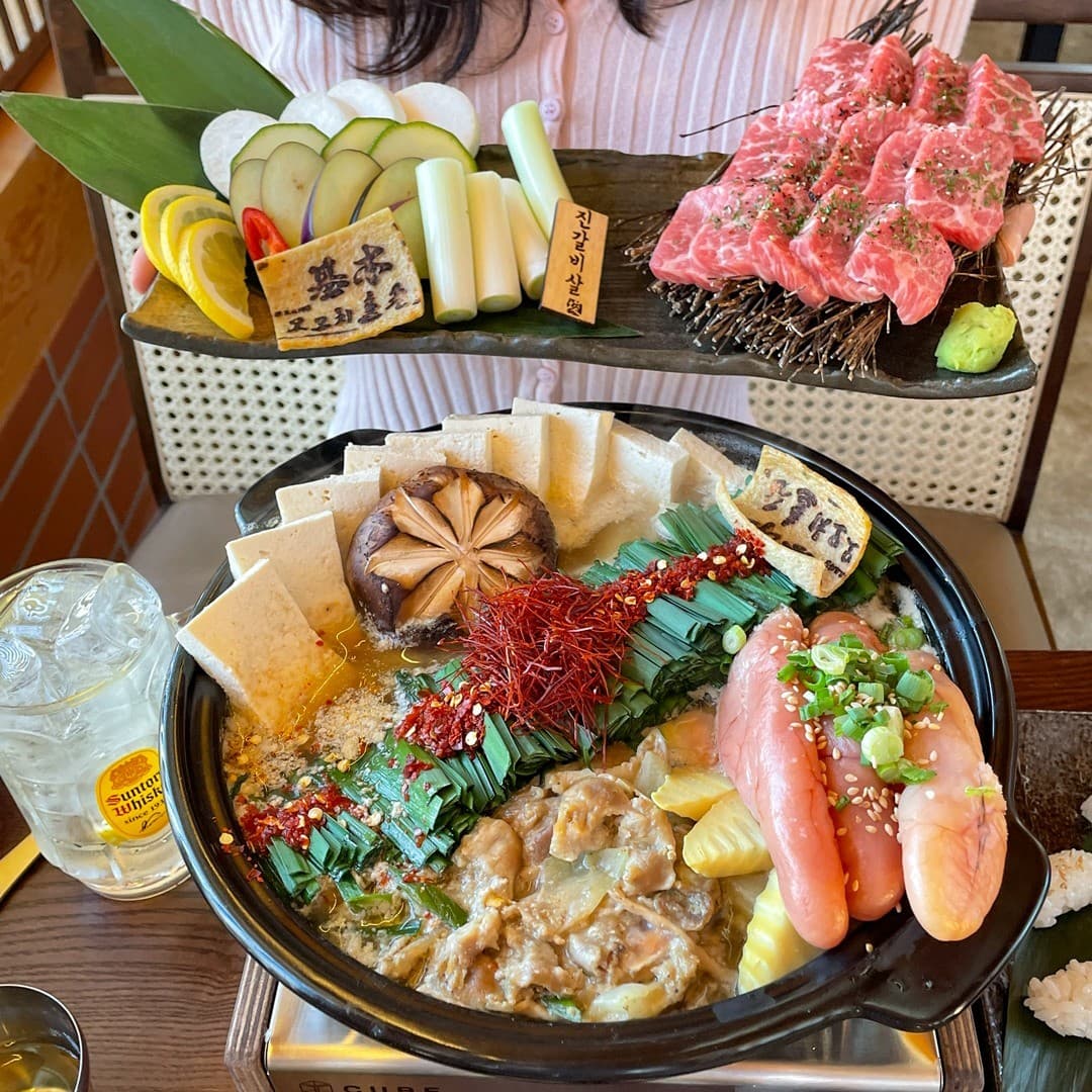 경상북도 경주시 모모치준 황남 경북 이자카야 다찌석 위 명란 모츠나베와 선홍빛 진갈비살, 하이볼. 조명 아래 1인 테이블에 차려진 식재료의 질감과 혼술 상황을 보여줌.