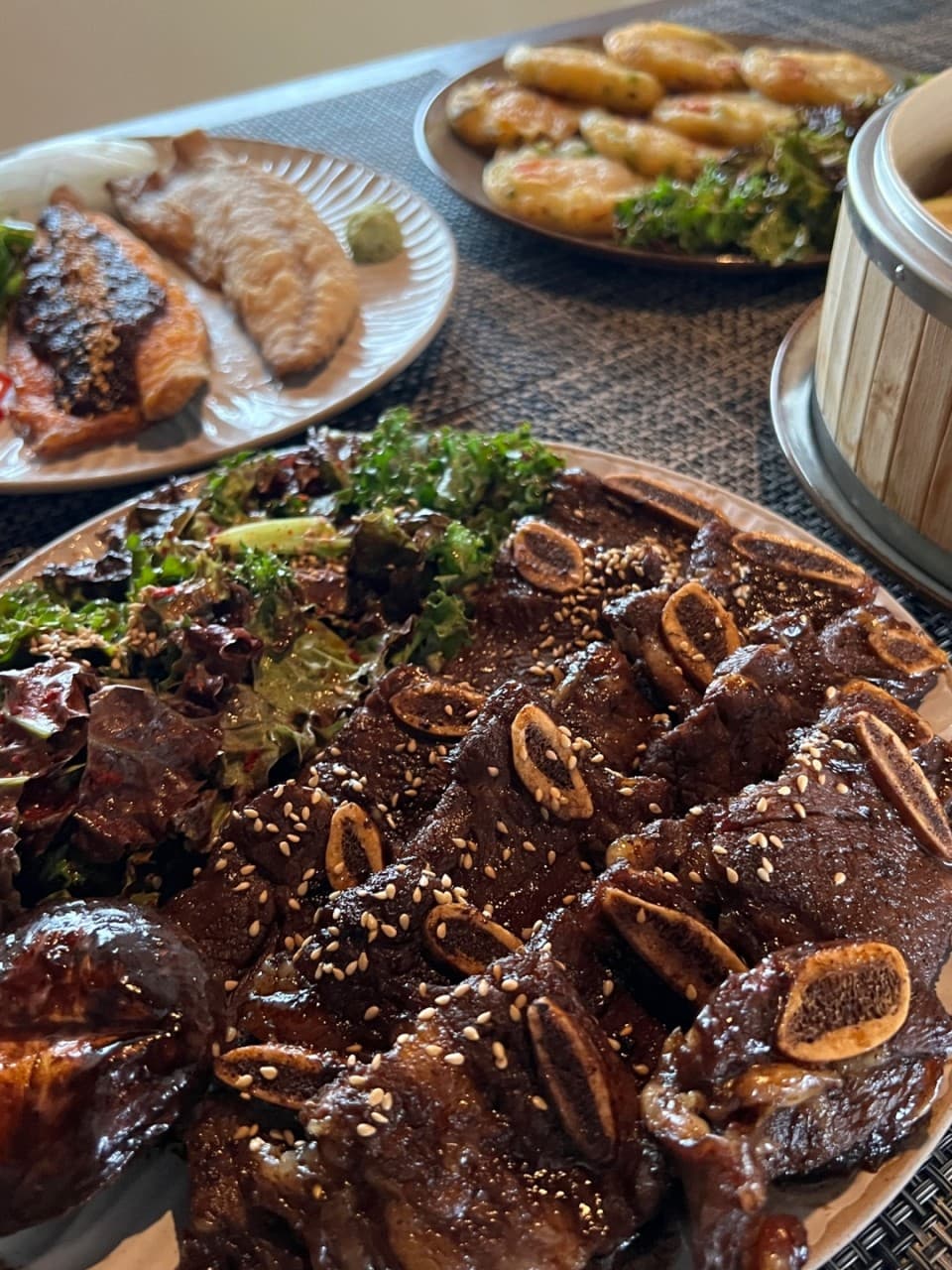 경상북도 경주시 요리주점 안다미로 경북의 다찌석 1인 혼술 차림. 윤기 나는 LA갈비와 참깨, 전, 생선구이가 차려진 식탁 위로 집중된 조명이 비치는 상황.