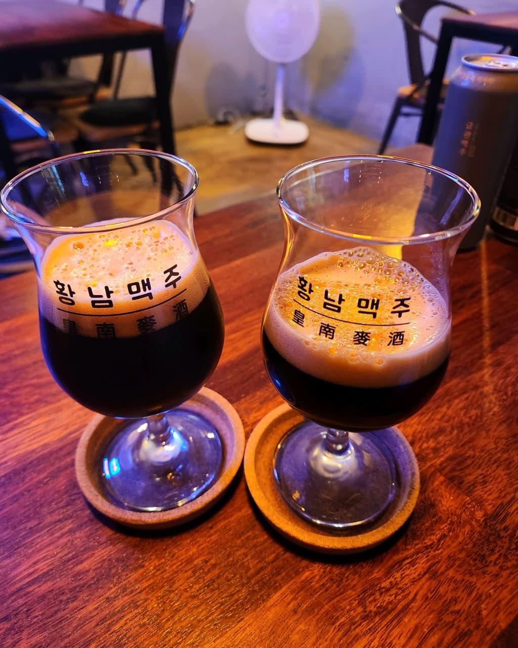 경상북도 경주시 황남맥주 경북 맥주 호프 매장 나무 테이블 위 거품 가득한 흑맥주 두 잔. 어두운 조명 아래 1인 좌석이 배치된 실내에서 혼술을 즐기는 상황.