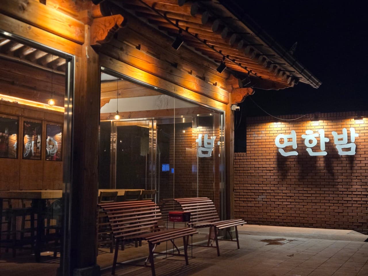 경상북도 경주시 연한밤 혼술바 경북 바(Bar) 건물. 한옥 처마 아래 주황색 조명과 벽돌 벽면의 간판. 통유리창 안쪽으로 1인석 다찌와 목재 테이블이 배치된 혼술 공간이 보임.