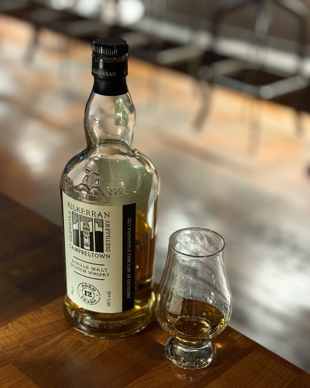 경상북도 안동시 레옹 정하점 경북 바(Bar) 다찌석 위 위스키 병과 잔. 조명이 비치는 나무 질감 테이블과 1인석 의자가 배치된 혼술 상황.