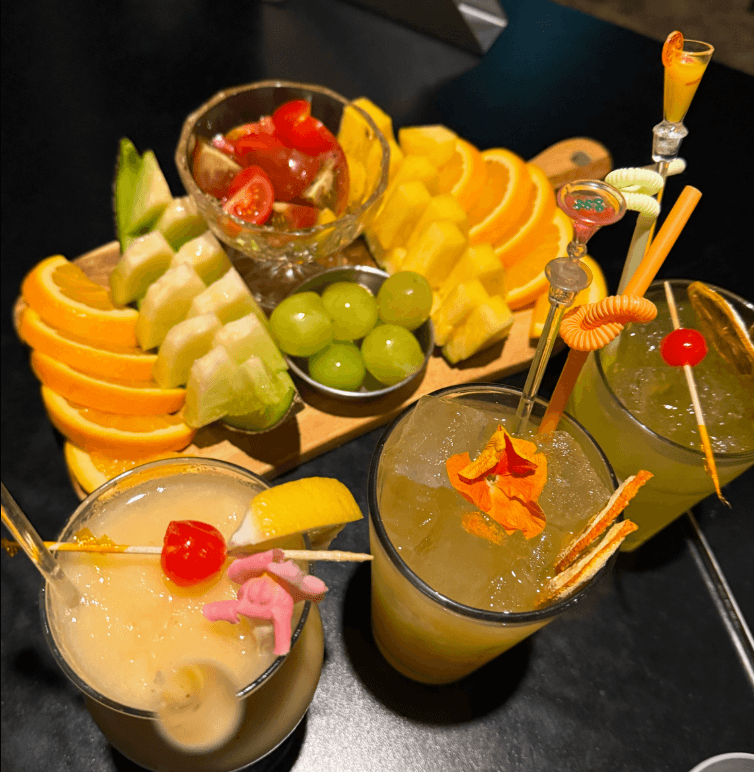 경상북도 경산시 비사이드 경북 바(Bar) 다찌석에 차려진 수분감 있는 과일 플래터와 칵테일. 은은한 조명 아래 1인 혼술을 즐기는 어두운 톤의 테이블 구성.