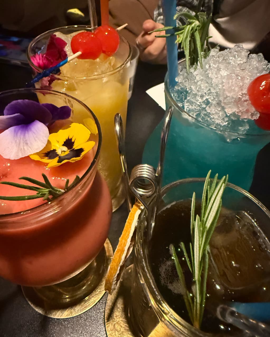 경상북도 경산시 비사이드 경북 바(Bar) 다찌석에 놓인 식용 꽃과 로즈마리 토핑 칵테일. 1인 혼술 상황의 붉고 푸른 색감 음료와 조각 얼음이 가득 담긴 유리잔.