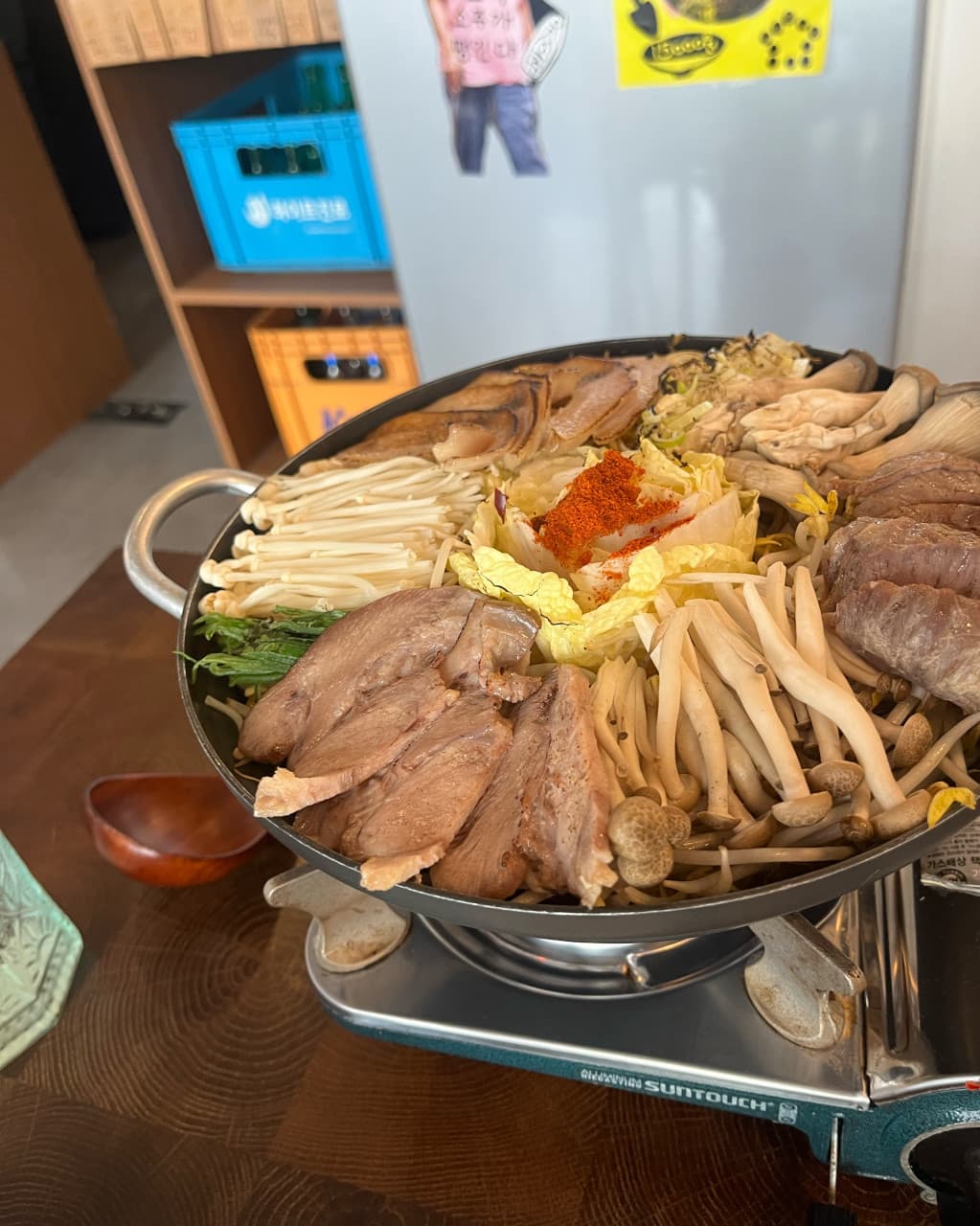 경기도 안양시 요리주점 이복실 경기 - 1인 다찌석 나무 테이블 위 가스버너와 버섯, 고기가 가득 담긴 전골 냄비. 혼술을 즐기는 식사 상황.