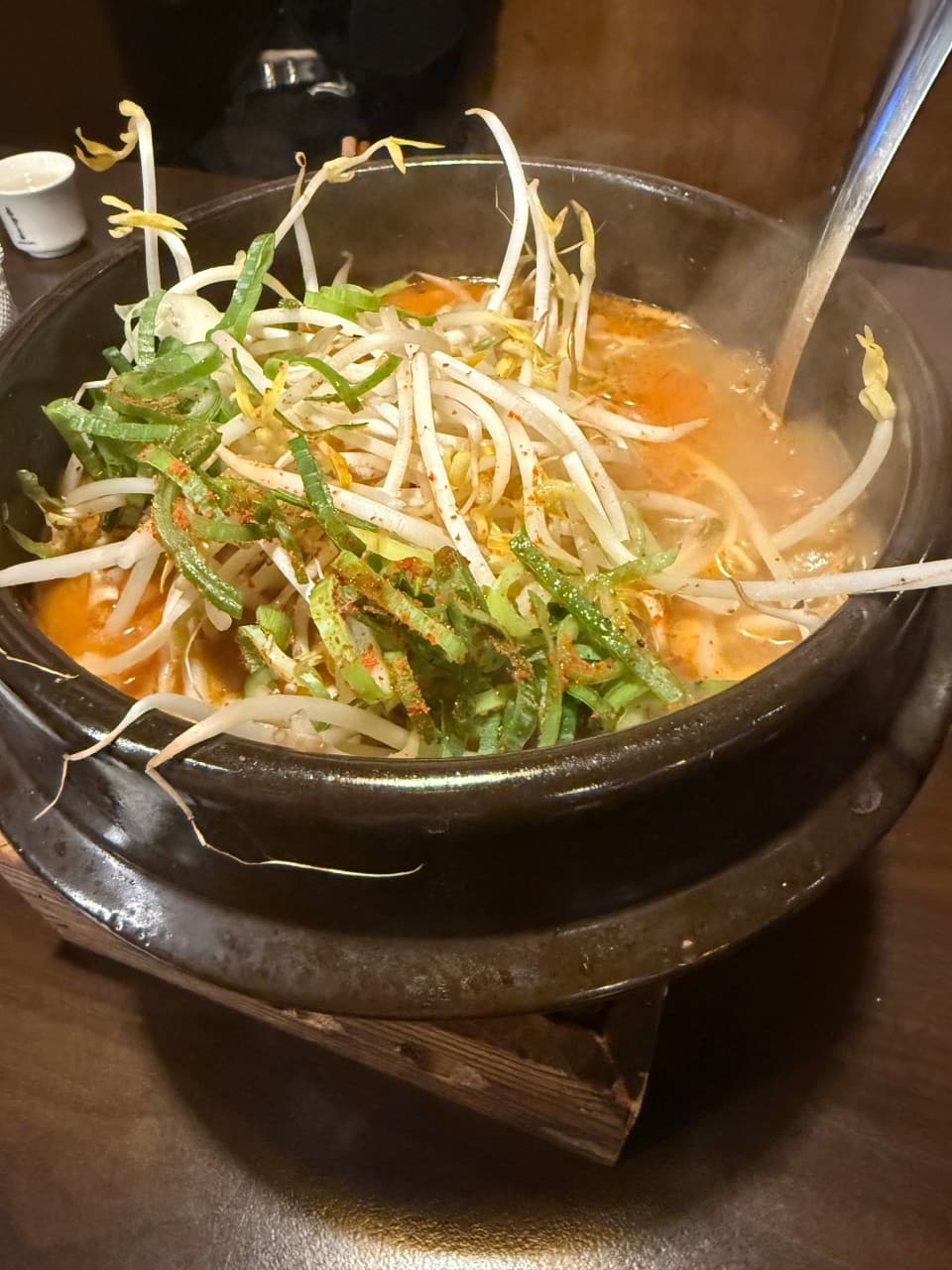 경기도 부천시 이자카야 철판오사카야 부천점 경기 다찌석 혼술 상황. 뚝배기에 담긴 숙주와 대파가 가득한 뜨거운 전골 요리와 조명이 비치는 질감을 보여줌.