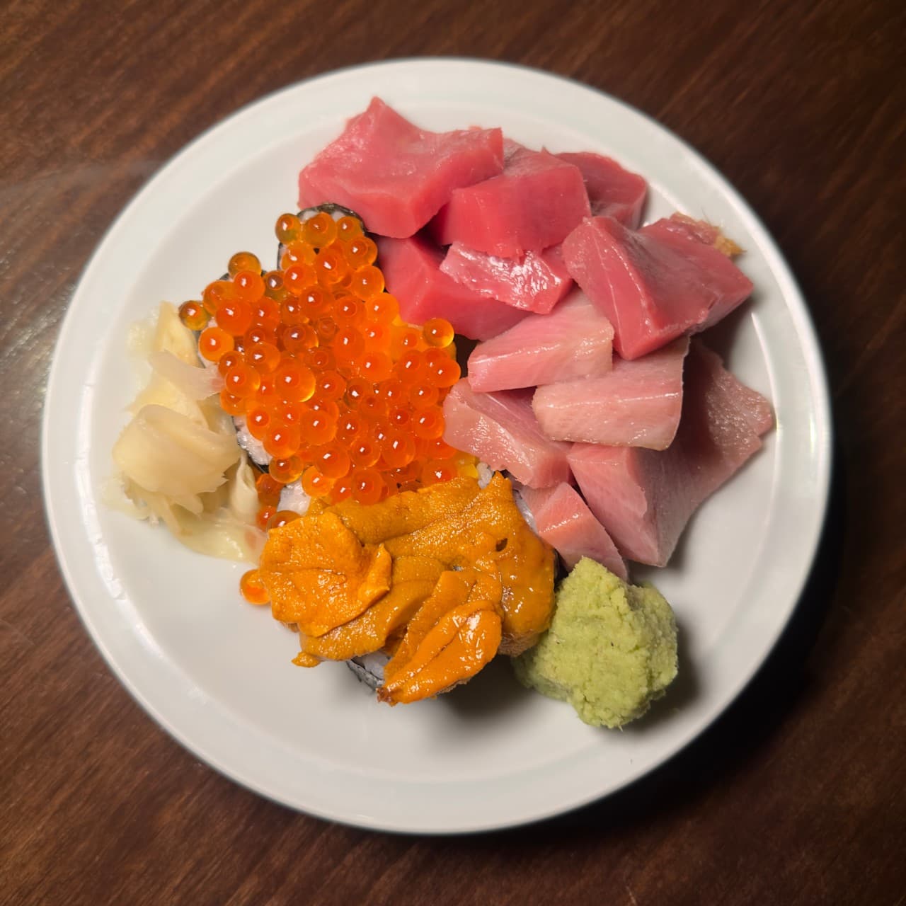부산광역시 수영구 초힛사츠 부산 이자카야 다찌석 혼술. 나무 식탁 위 조명을 받아 윤기가 도는 참치, 성게알, 연어알 1인 사시미의 질감과 어두운 배경의 대비.