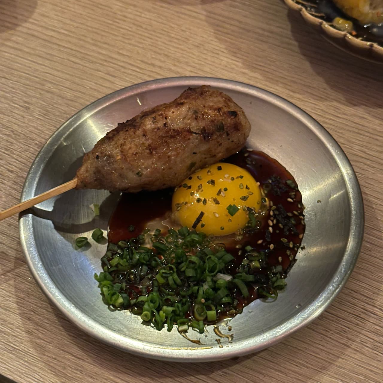 부산광역시 부산진구 요리주점 앙요 전포본점 부산의 나무 테이블 위 금속 접시에 담긴 노른자 소스와 1인용 꼬치. 다찌석 조명 아래 혼술하는 상황
