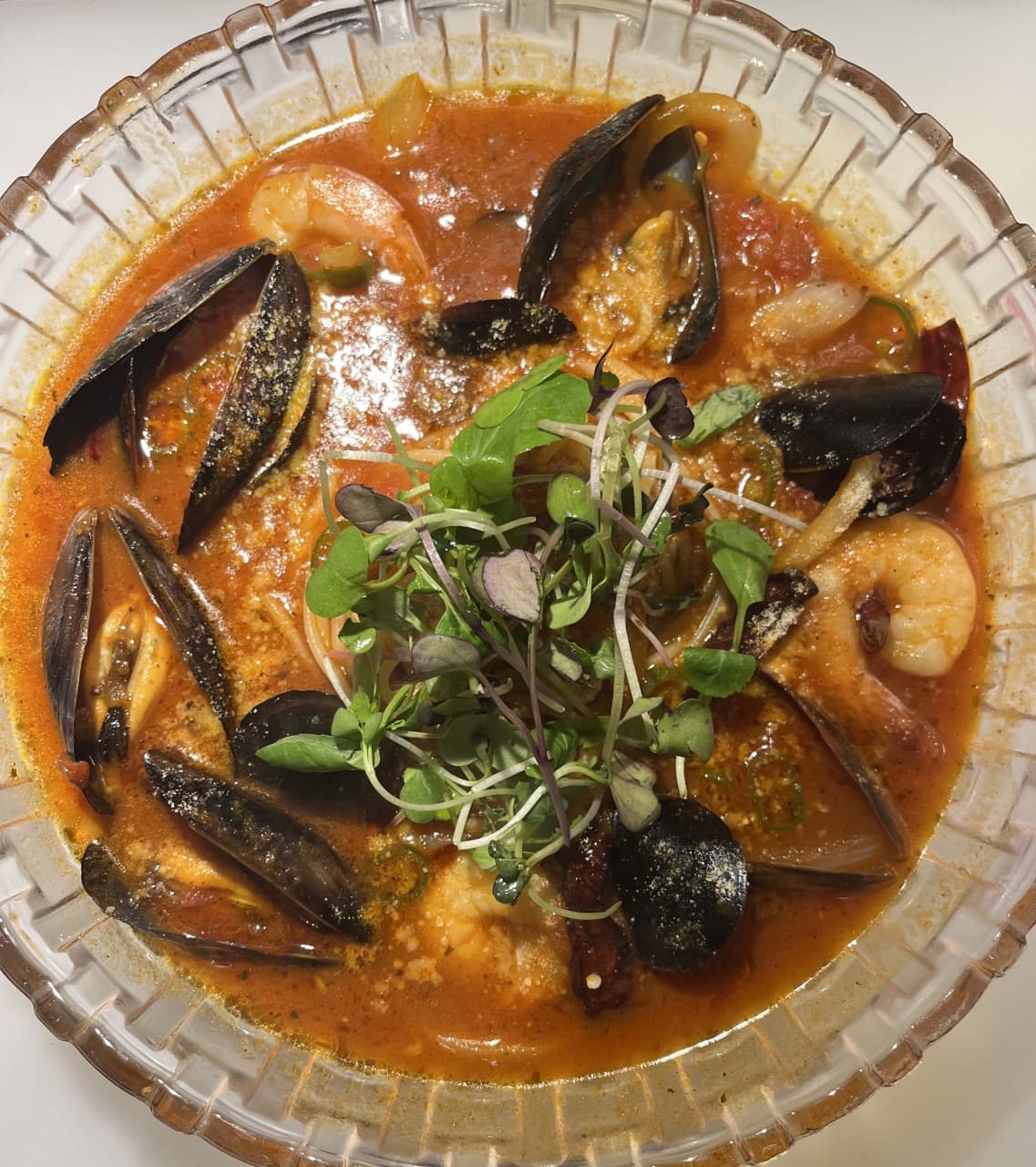부산광역시 수영구 요리주점 수달바 광안 부산 다찌석에서 즐기는 1인 혼술. 조명 아래 홍합과 새우가 담긴 매콤한 해산물 요리와 어린잎 채소의 구성을 보여줌.