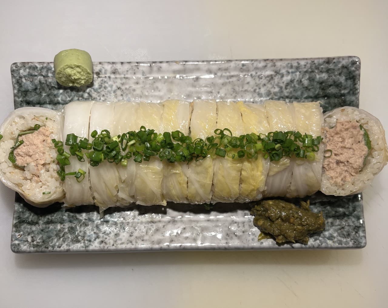 부산광역시 수영구 요리주점 수달바 광안 부산 다찌석 1인 혼술 메뉴 묵은지 참치롤. 밝은 조명 아래 사각 접시 위 백김치와 쪽파 고명이 올라간 음식의 단면.
