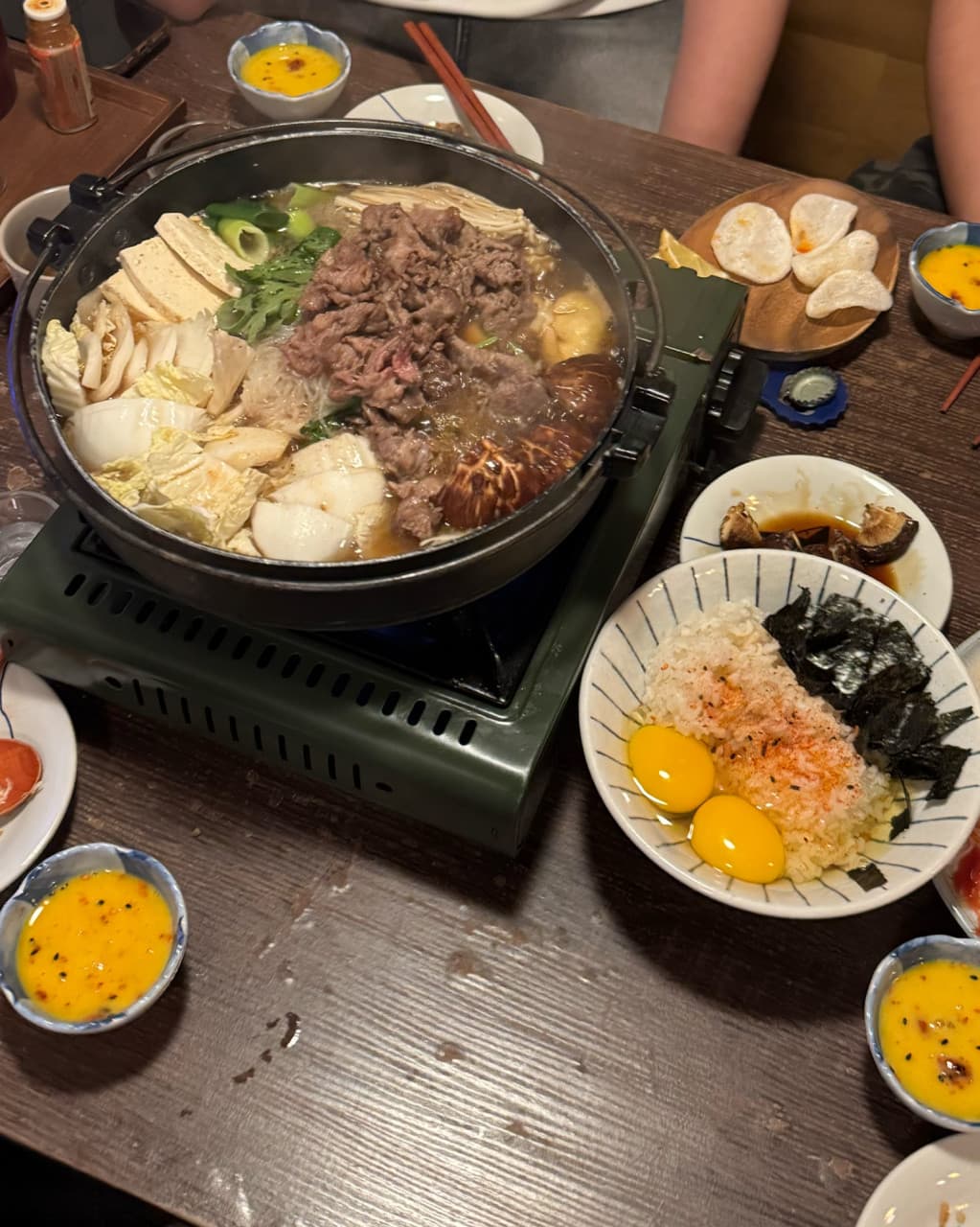 대구광역시 동구 요시쿠 신서 본점 대구 이자카야 1인 수키야키. 조명 아래 나무 테이블 위 버너에서 끓는 소고기 전골과 표고버섯, 노란 달걀노른자 소스.