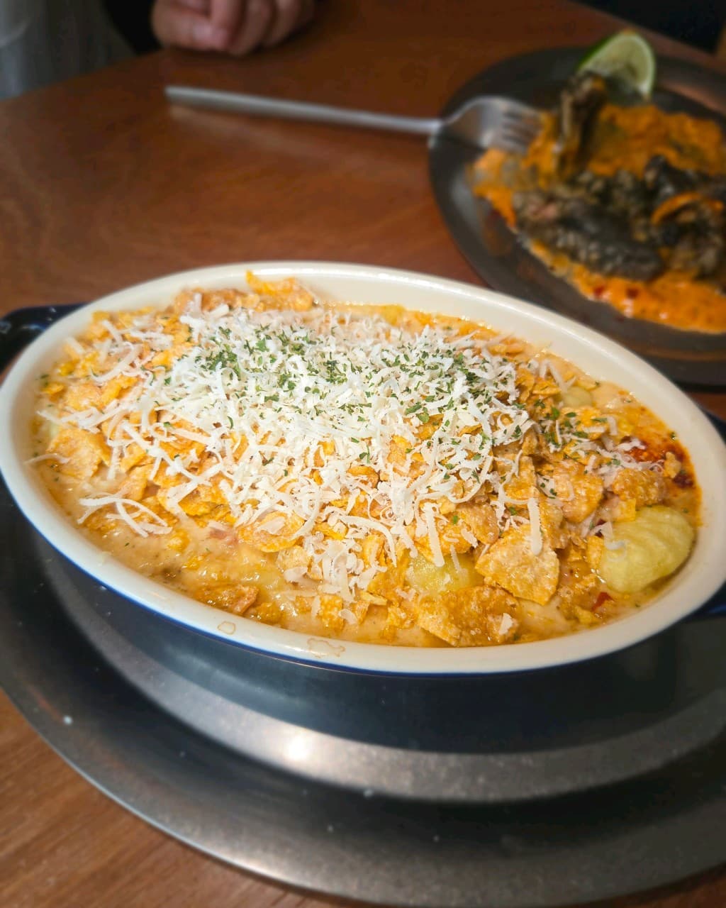 부산광역시 수영구 표류 부산 바(Bar) 다찌석에서 즐기는 1인 혼술. 오렌지빛 조명 아래 치즈 가루와 바삭한 플레이크가 듬뿍 올라간 크림 안주의 질감이 목재 테이블 위에서 선명하게 나타남.