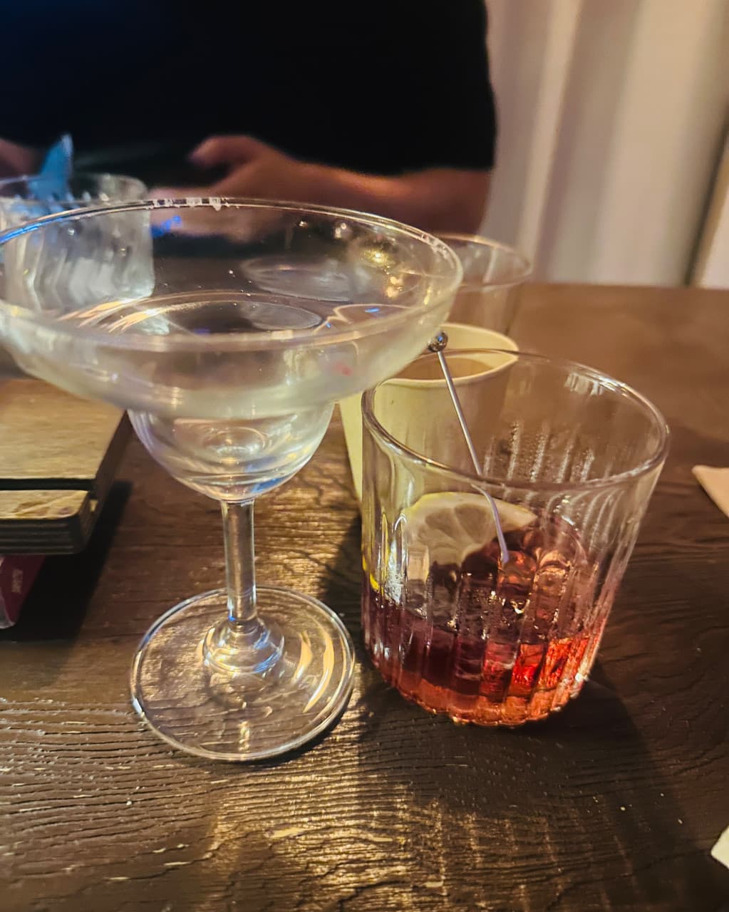 부산광역시 수영구 곁 부산혼술바 광안리점 바(Bar) 다찌석 조명 아래 레몬 슬라이스가 담긴 붉은 칵테일과 투명한 잔이 놓인 1인 혼술 테이블