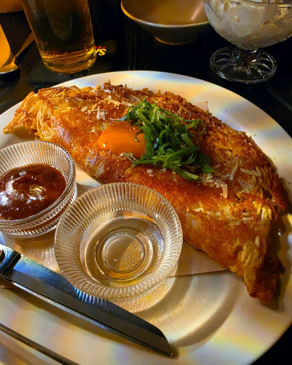 대전광역시 서구 혼술 이자카야 비어스탠드쿠모와리 대전 - 다찌석 조명 아래 바삭한 질감의 안주와 계란 노른자, 맥주가 차려진 1인 식사 상황