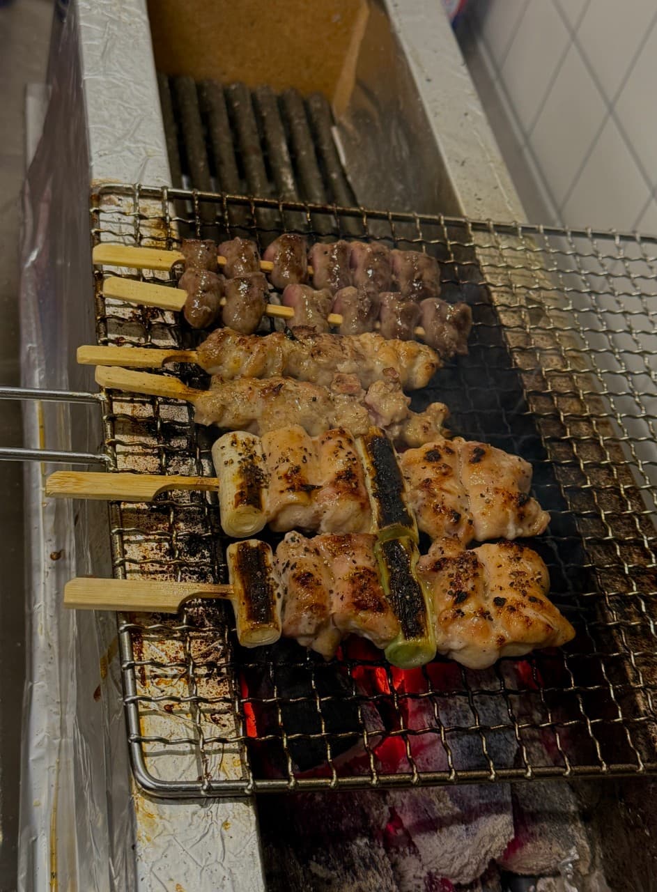 대전광역시 중구 이자카야 요모 대전대흥점 다찌석 숯불 위에서 구워지는 닭꼬치. 붉은 숯불 연기와 육즙이 맺힌 1인 혼술용 꼬치구이가 나열된 모습.