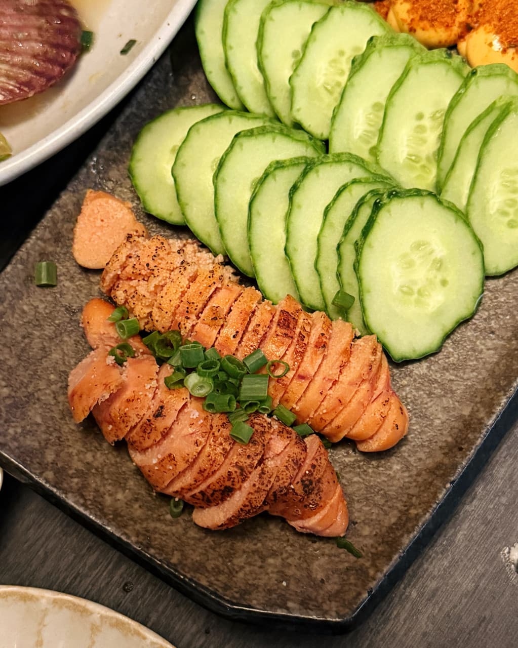 대전광역시 중구 이자카야 미쇼쿠 대전 다찌석 혼술 상황. 조명 아래 노릇한 명란구이와 오이가 1인석 목재 테이블 위 접시에 담겨 있다.