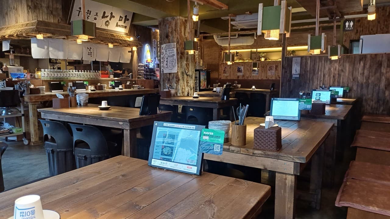 인천광역시 남동구 한식주점낭만 구월점 인천 요리주점 내부. 나무 소재 1인 다찌석과 테이블에 비치는 노란 조명 아래 태블릿 메뉴판이 배치된 혼술 현장.
