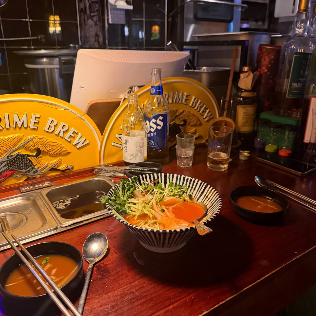 인천광역시 연수구 요리주점 철길부산집 송도타임스페이스점 인천의 황색 조명 아래 1인 다찌석. 매콤한 국물 요리와 맥주가 차려진 혼술 상차림.
