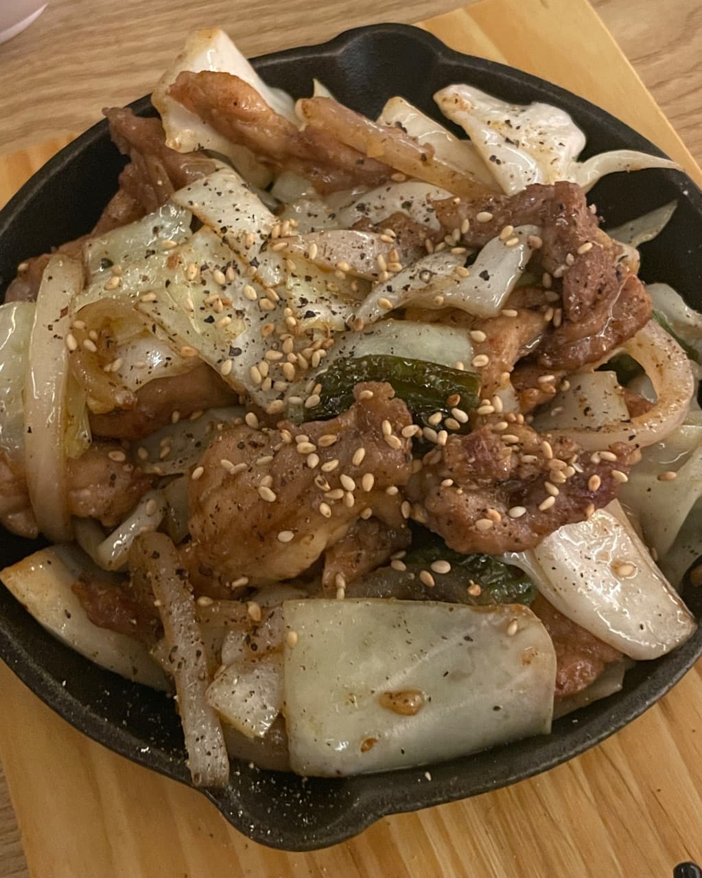 인천광역시 남동구 혼술 요리주점 하나마토 인천논현 - 조명 아래 다찌석 철판 위 깨와 후추를 뿌린 고기와 양배추의 질감이 드러나는 1인 차림