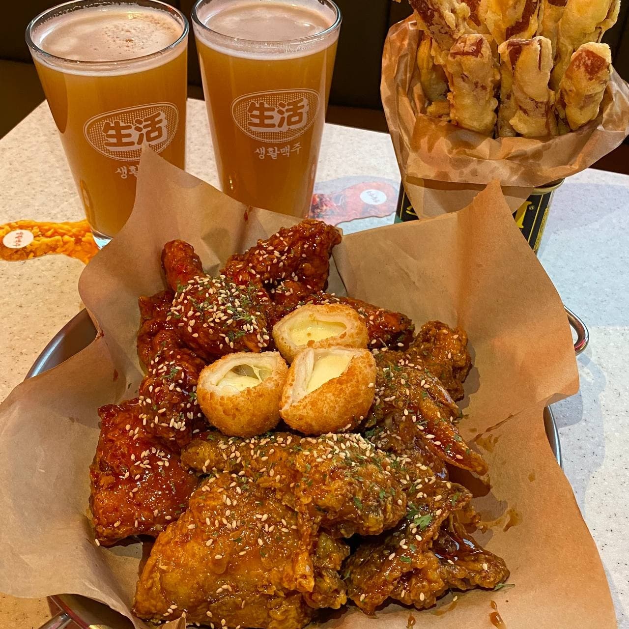 인천광역시 연수구 생활맥주 송도더샵엘테라스점 인천 맥주 호프. 다찌석 조명 아래 차려진 1인 혼술 세트로 바삭한 양념 치킨과 치즈볼, 거품 가득한 수제 맥주가 놓인 상황.
