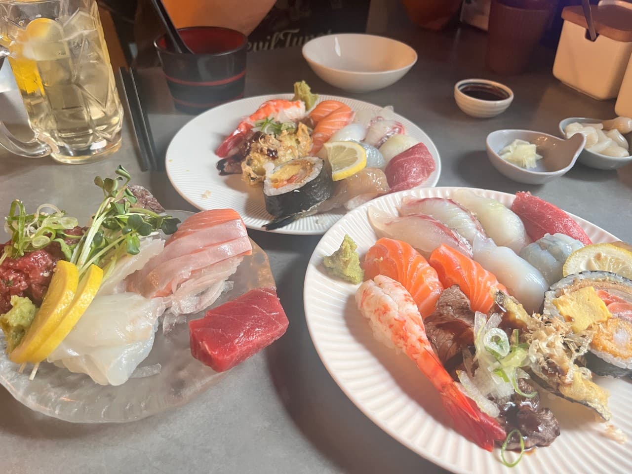 제주특별자치도 제주시 이자카야 정직한초밥 드림타워노형본점 제주 다찌석 1인 혼술. 조명 아래 윤기 나는 사시미와 모듬 초밥, 레몬이 담긴 하이볼이 차려진 테이블.