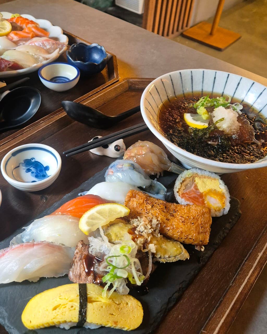 제주특별자치도 제주시 정직한초밥 드림타워노형본점 제주 이자카야 1인 다찌석의 모둠 초밥과 냉모밀 세트. 조명 아래 연어와 유부초밥의 질감이 강조된 혼술 식사.