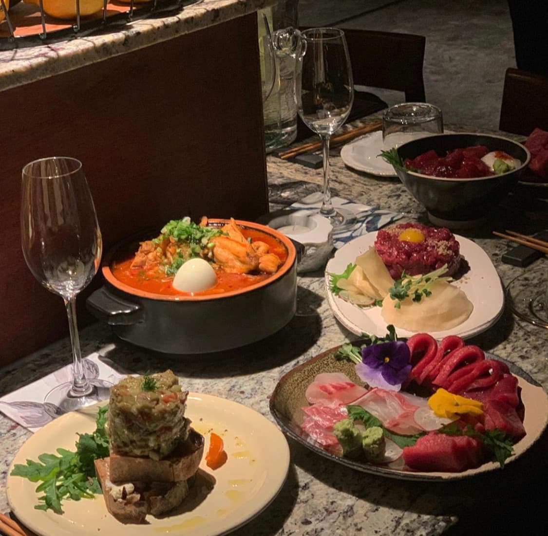 제주특별자치도 제주시 이자카야 정대 제주 다찌석에 차려진 사시미와 육회. 은은한 조명 아래 혼술을 위한 1인 테이블 구성과 전골의 질감이 돋보이는 대리석 카운터석.