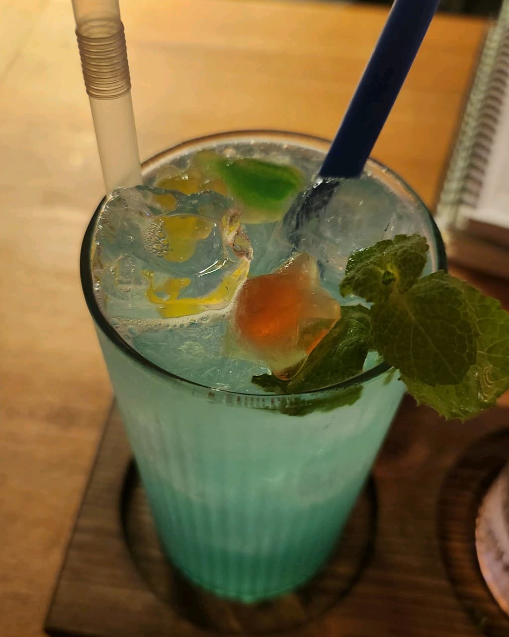 제주특별자치도 서귀포시 자유의지 혼술바 제주서귀포점 바(Bar) 다찌석 혼술. 조명 아래 얼음과 민트가 담긴 푸른색 하이볼의 액체 질감과 우드 테이블.