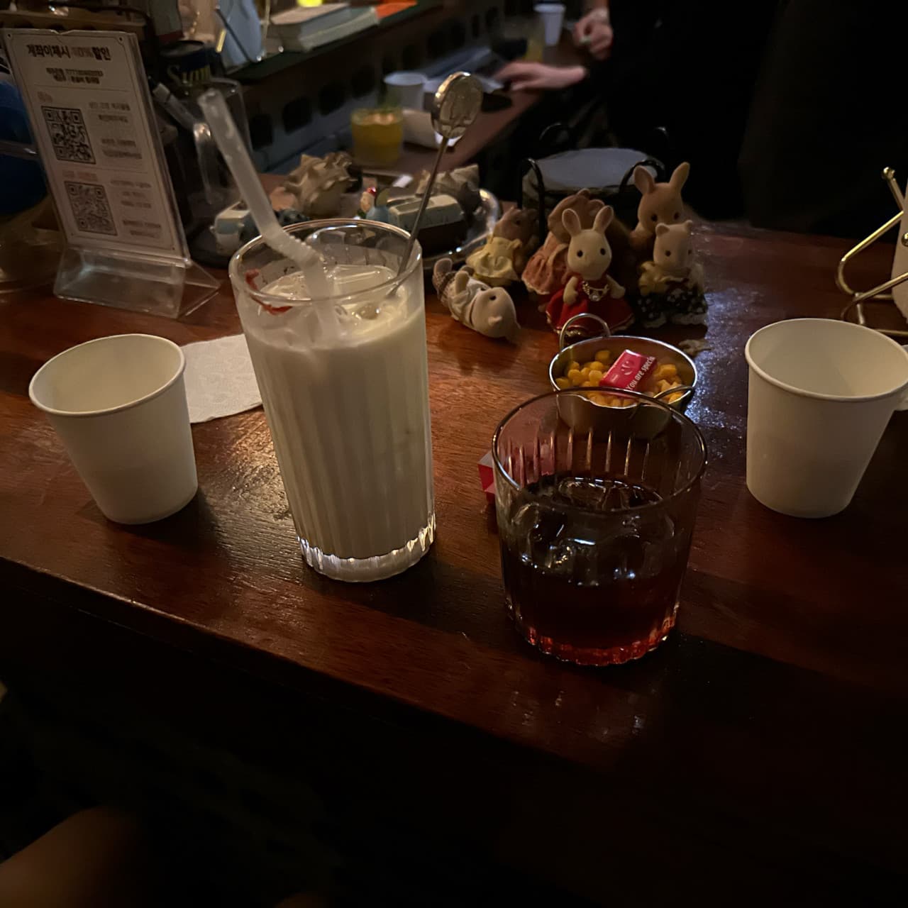 제주특별자치도 제주시 제주아홉 혼술바 본점 협재점 바(Bar) 다찌석 혼술. 조명 아래 우유빛 음료와 얼음 담긴 잔, 토끼 소품이 놓인 나무 카운터 1인석 현장.