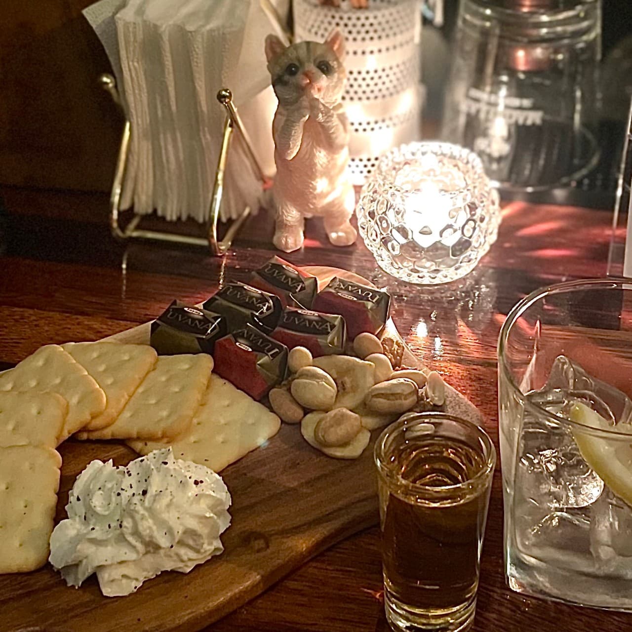 제주특별자치도 제주시 제주아홉 혼술바 본점 협재점 바(Bar) 다찌석의 혼술. 촛불 아래 크래커와 꾸덕한 크림치즈, 초콜릿 안주가 담긴 목재 트레이와 하이볼 잔이 놓인 상황.
